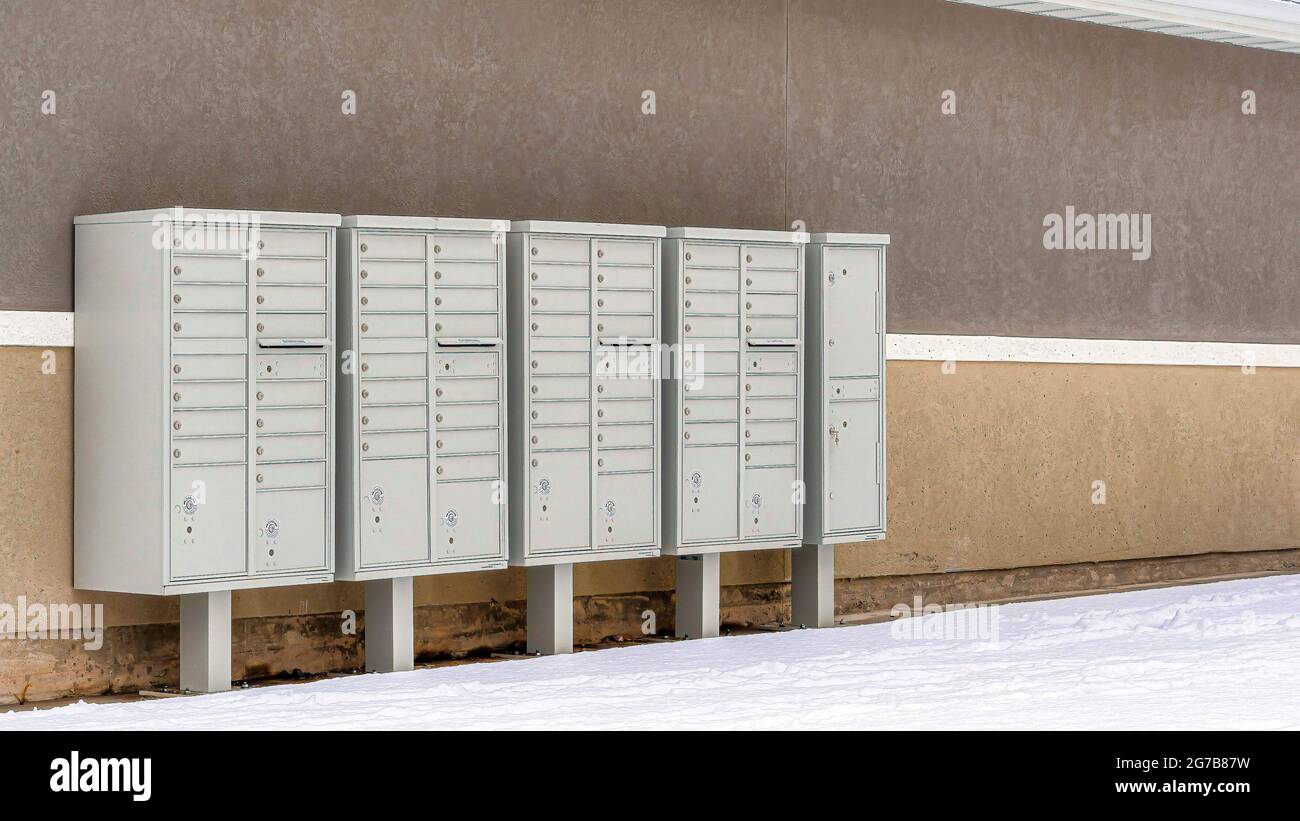 Pano Cluster Metallpostfächer mit Sockeln an der Wand des Gebäudes mit verschneiten Dach Stockfoto