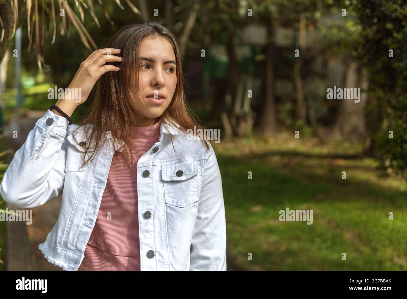 Porträt eines Teenagers mit Zahnspangen im Freien, das ihr glattes Haar mit der Hand kämmt Stockfoto