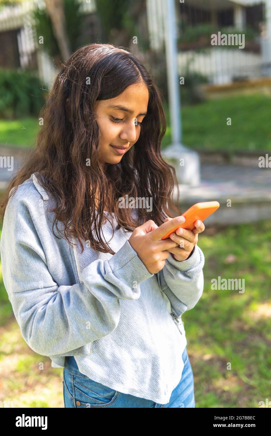 Latina brünette teen Mädchen mit ihrem Smartphone in einem Morgen im Freien Stockfoto