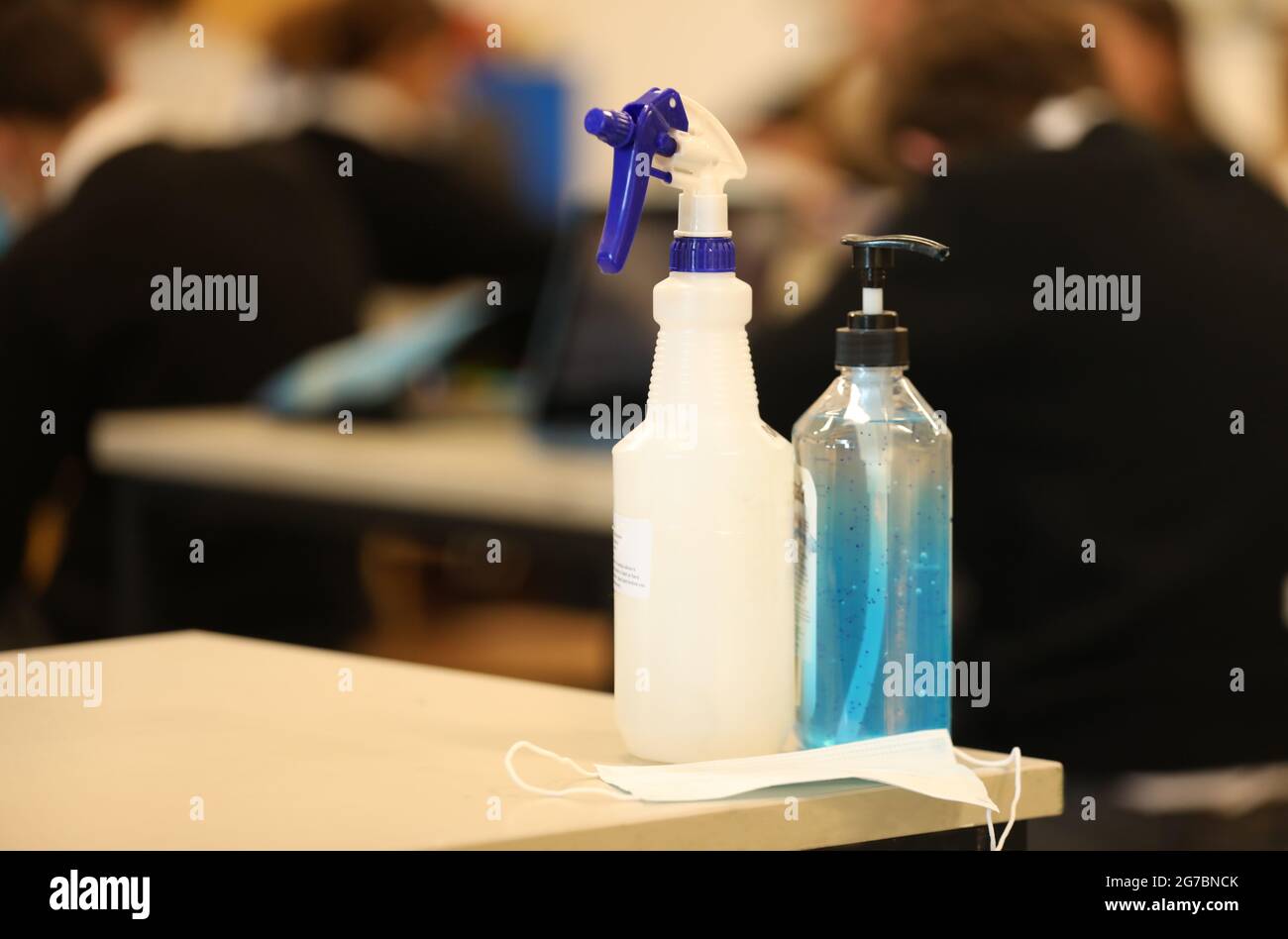 Ein Blick in ein Schulzimmer mit Händedesinfektionsmittel und Gesichtsmaske auf einem Schreibtisch. Covid Corona Virus sichere Schule oder Lernen. Stockfoto
