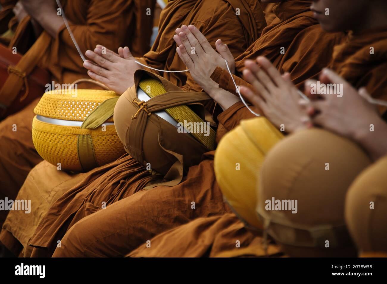 Viele Mönche drücken ihre Hände zusammen, um zu beten, bevor die Menschen Almosen an den Mönch geben Stockfoto