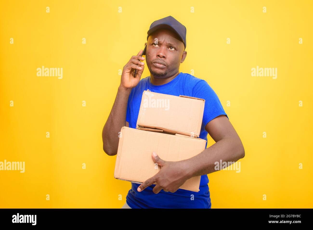 Ein afrikanischer Entsendungsmann mit Rucksack, der einen Anruf abgab, Boxen trug und eine Gesichtskappe trug Stockfoto