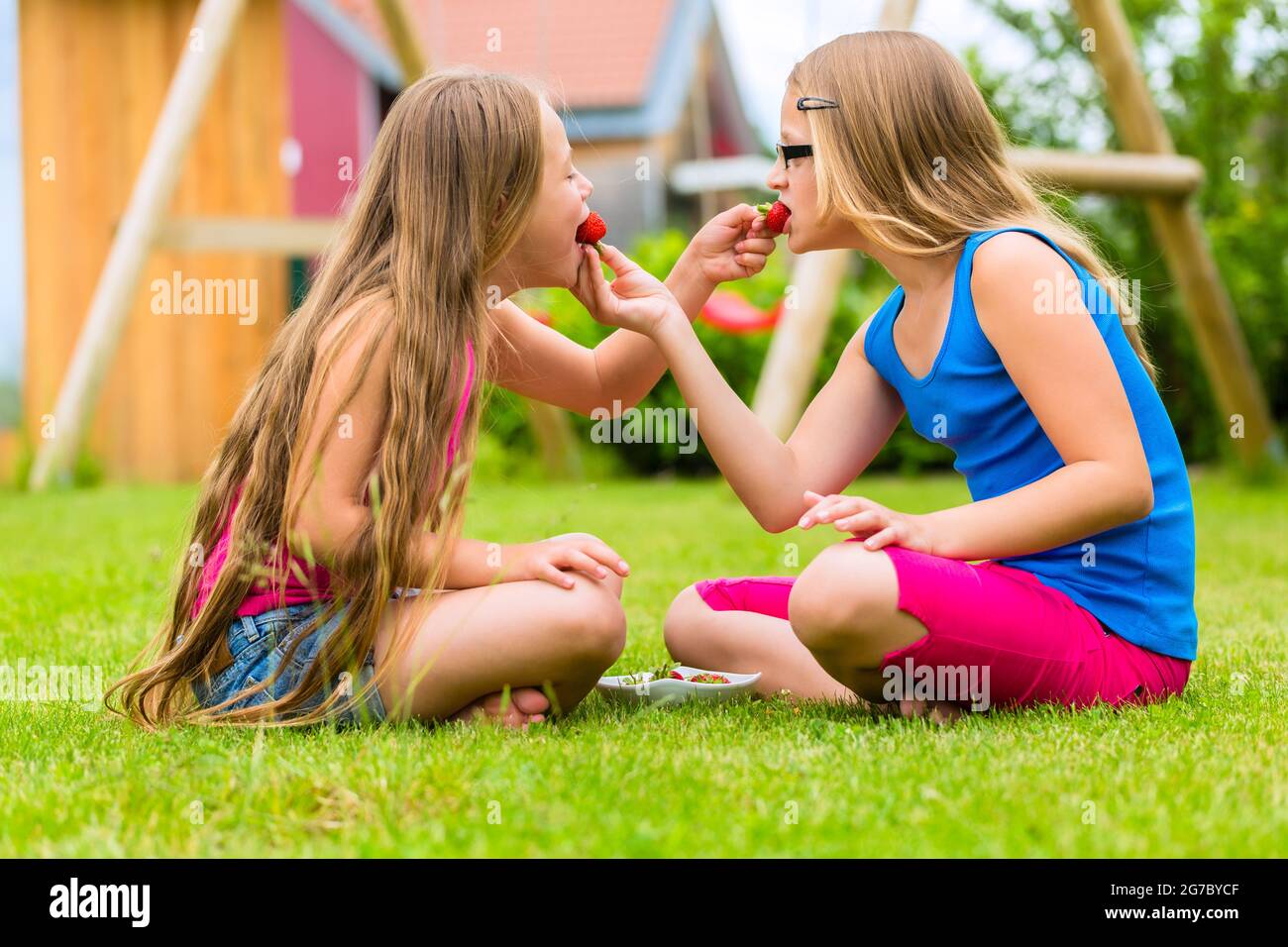 Glückliche Mädchen oder Schwestern zu spielen zu Hause, im Garten und Essen Erdbeeren Stockfoto