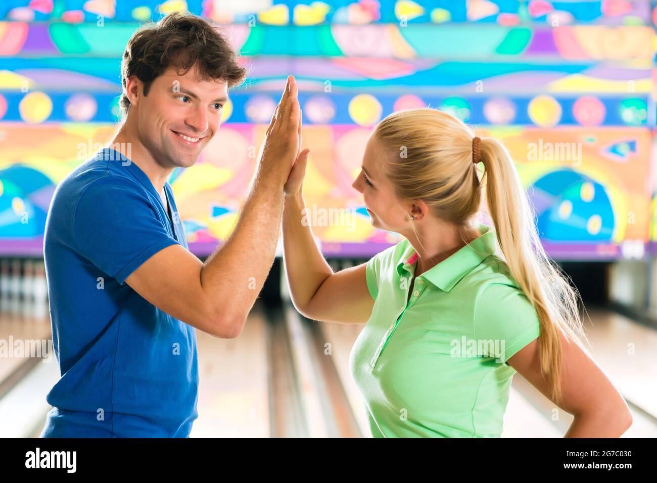 Junges Pärchen oder Freunde, Mann und Frau, vor der Gasse 10 Pin Bowling spielen sie sind ein Team Stockfoto