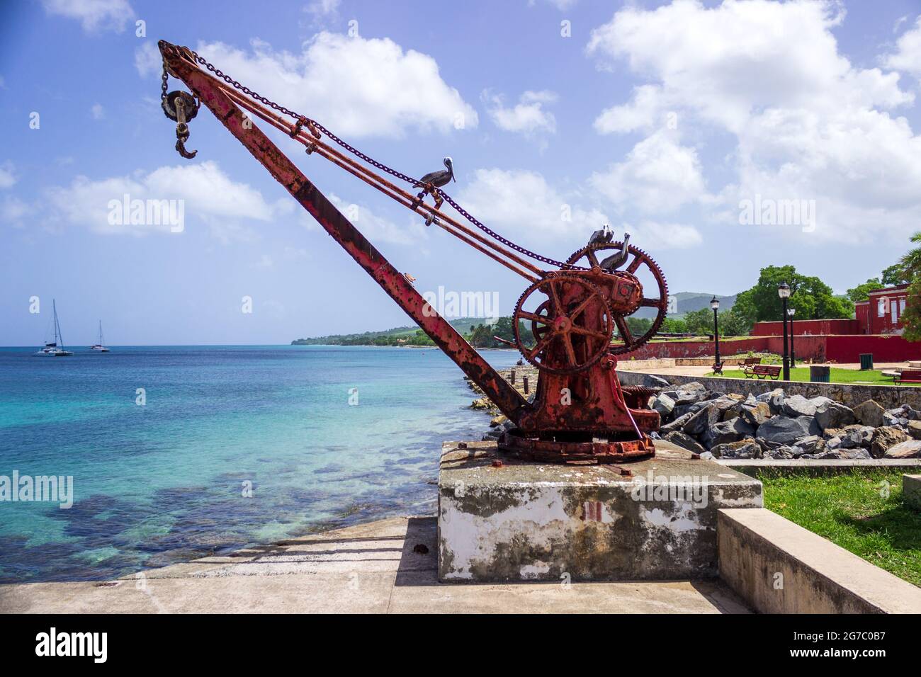 Ein Pelikan sonnt sich in der Sonne, während er auf einem alten Hafenkran am Pier in Frederiksted, St. Croix, USVI, thront. Stockfoto