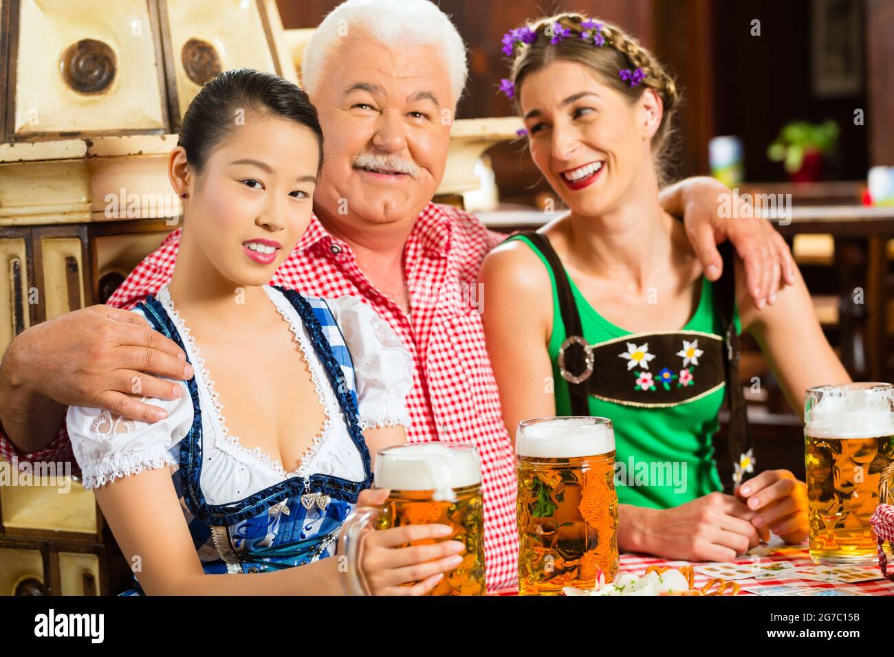 Im Pub - Freunde in Tracht, Dirndl und Lederhosen ein frisches Bier in Bayern, Deutschland Stockfoto