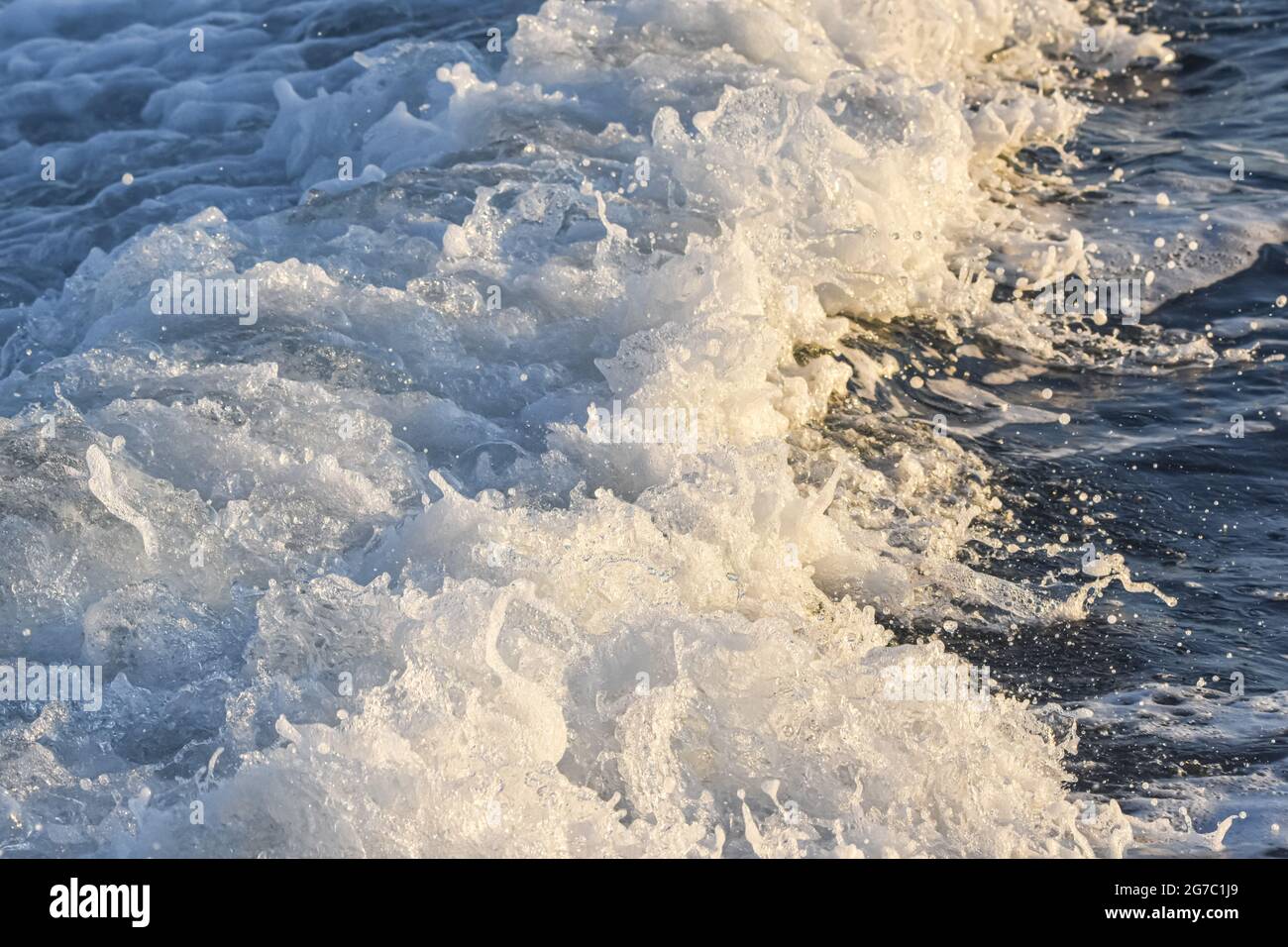 Im Gefolge eines großen Schiffes wurde das Meerwasser zu einem Schaum. Am späten Nachmittag goldenes Licht. Stockfoto