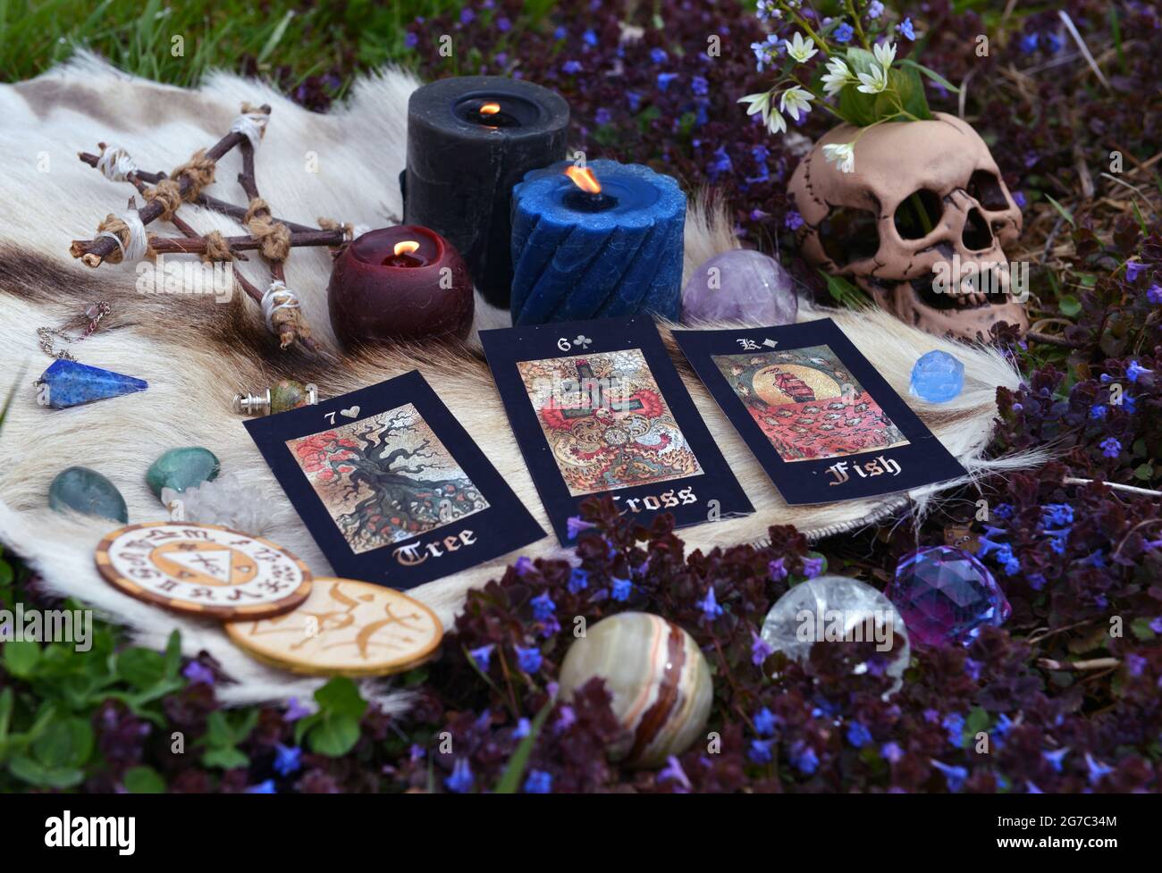 Beltane Ritual mit Tarot-Karten, Totenkopf, brennenden Kerzen, Pentagramm und Kristallen draußen. Esoterischer, gotischer und okkulter Hintergrund, Halloween Mystiker und Stockfoto
