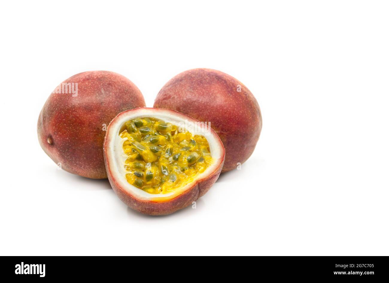Passionsfrucht in der Gruppenanzeige wird eine aufgeschnittene Passionsfrucht mit zwei ganzen Früchten zusammengestellt, Bild ein weißer Hintergrund, Nahaufnahme, um Details zu sehen. Stockfoto