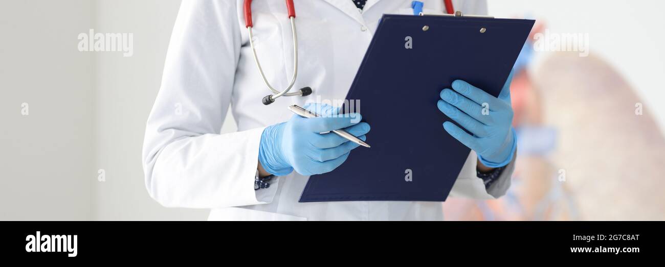 Hände des Arztes in Schutzhandschuhen halten Klemmbrett und Stift Stockfoto Hände des Arztes in Schutzhandschuhen halten Klemmbrett und Stift Stockfoto