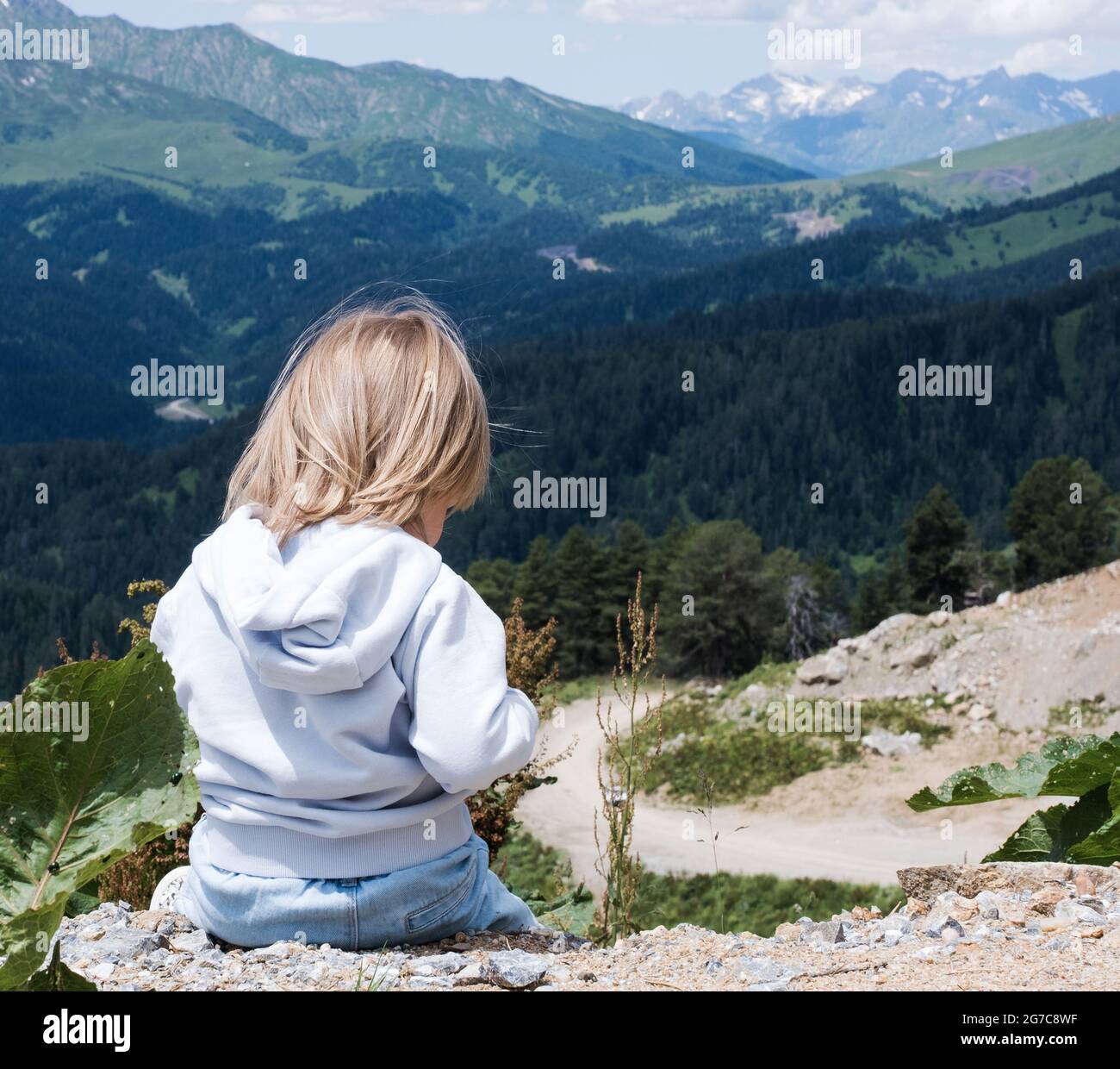 Das Kind sitzt und blickt auf die Landschaft des Kaukasus. Reisen im Freien, Reisen vor Ort. Stockfoto