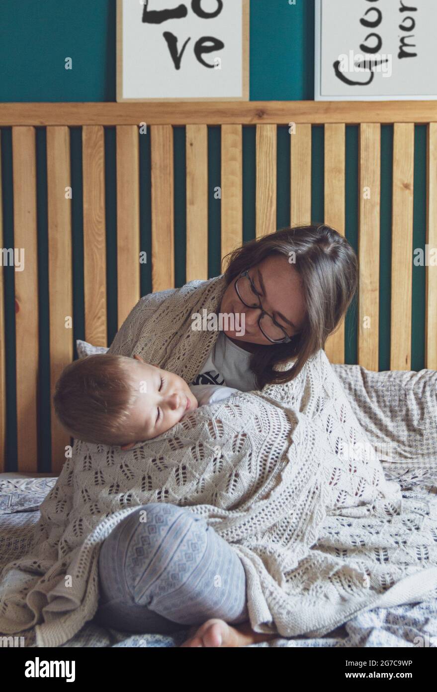 Mama und Kind haben Spaß im Schlafzimmer auf dem Bett unter dem Rohling Stockfoto