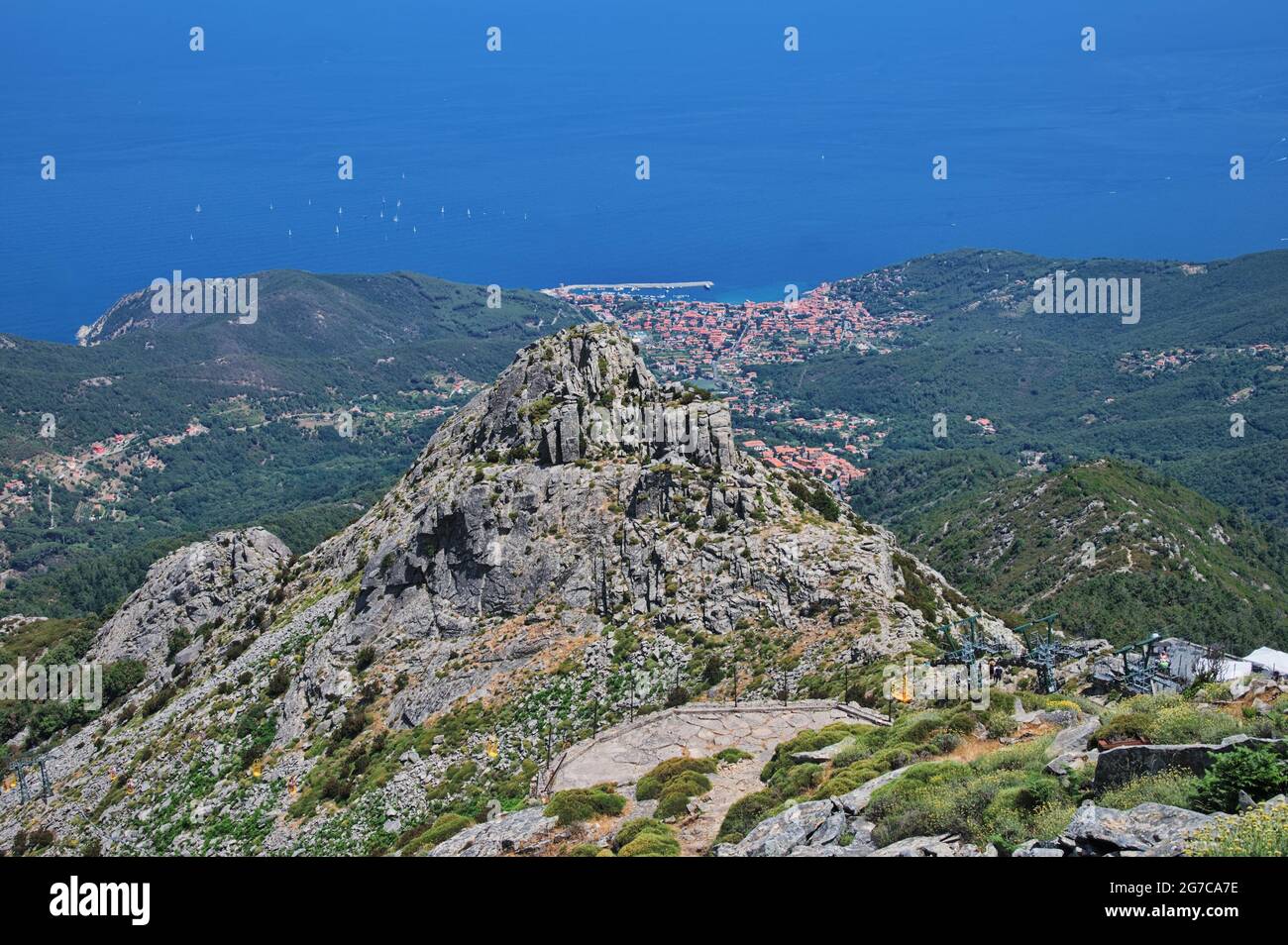 Felsiger Berggipfel mit mediterranem Meer und kleinem Dorf im Hintergrund Stockfoto