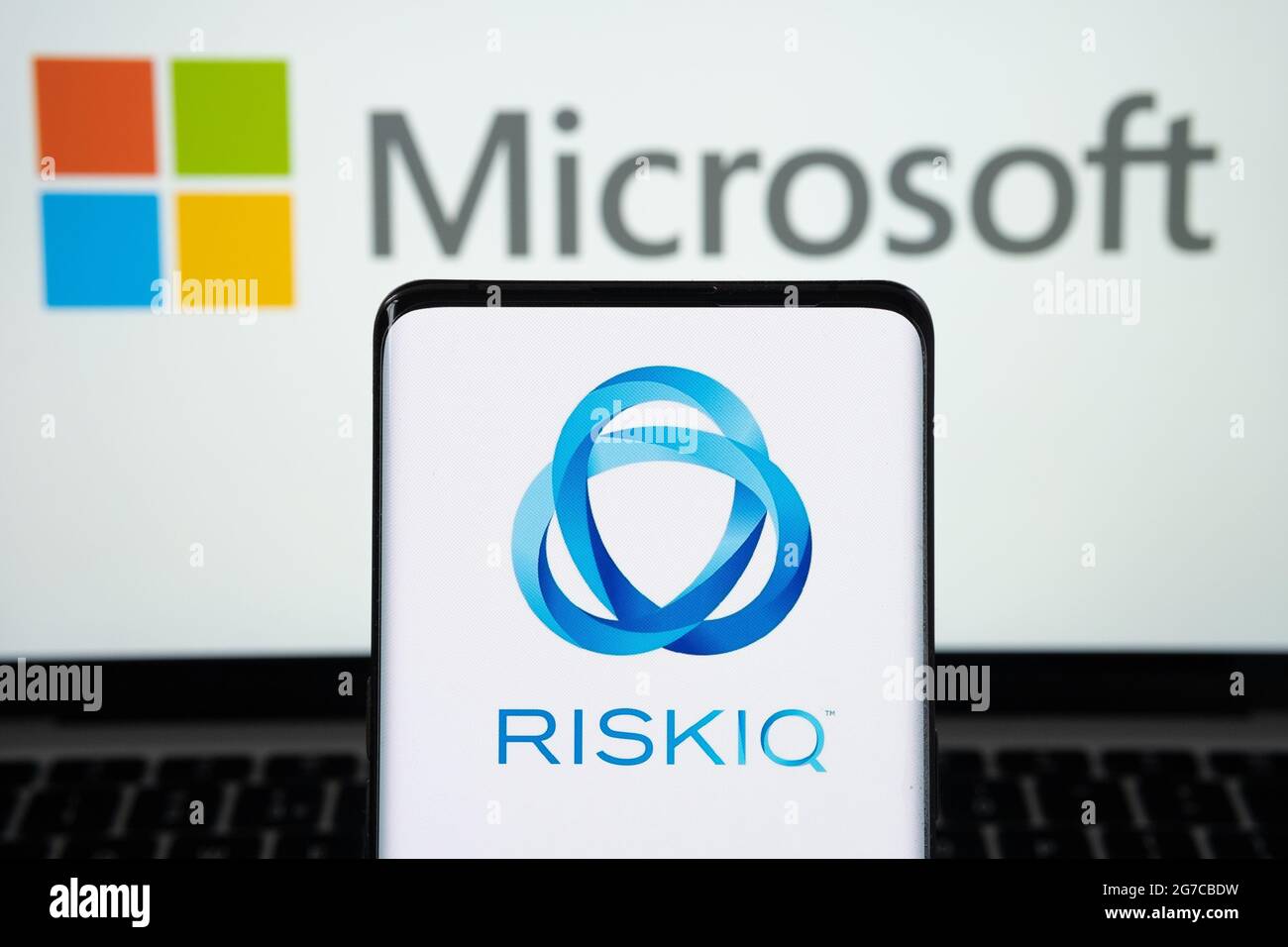 Das Unternehmenslogo von RiskIQ auf dem Smartphone und das Microsoft-Logo auf dem verschwommenen Laptop. Konzept für Unternehmenskauf. Stafford, United Kigdom, 13. Juli 20 Stockfoto