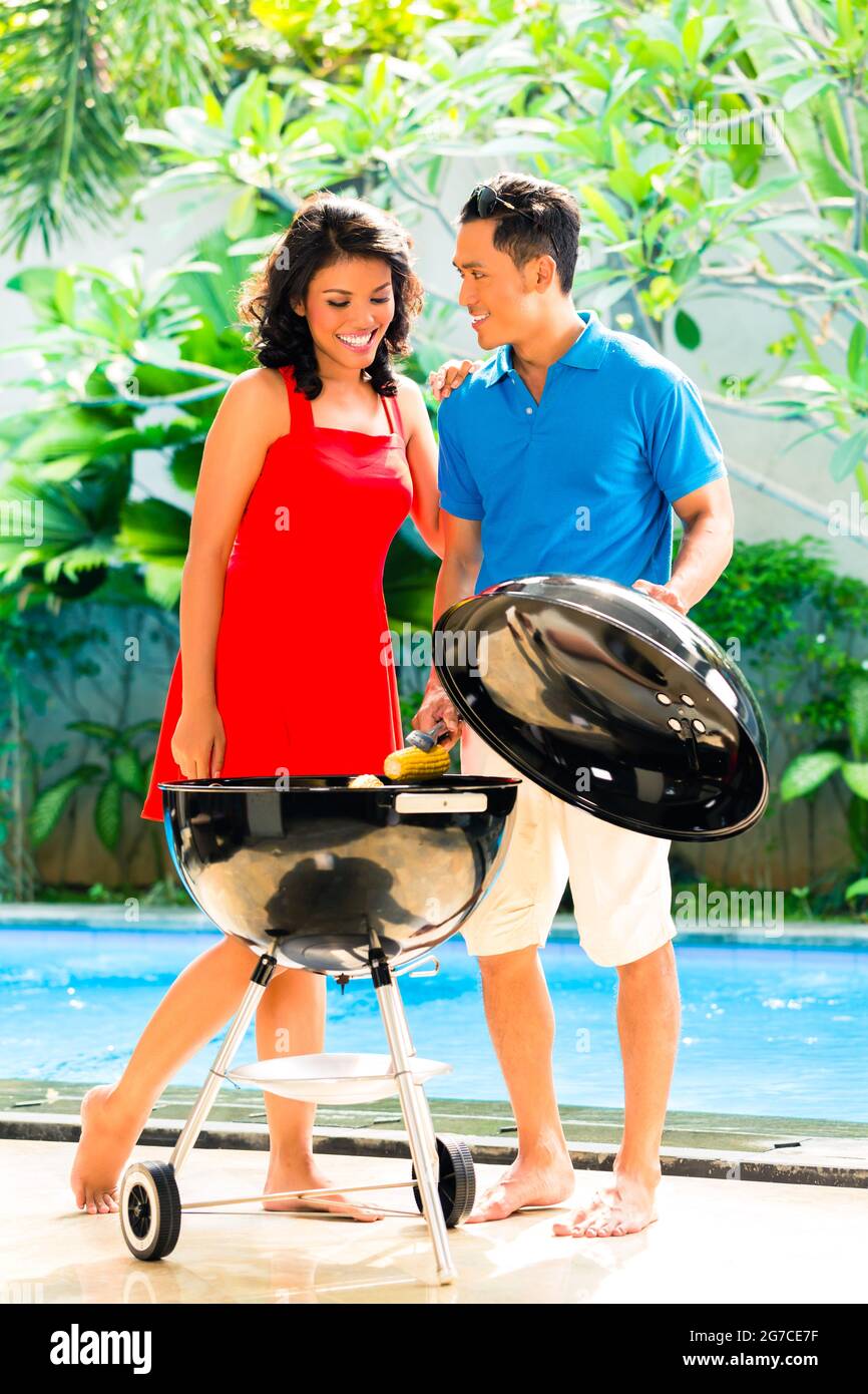 Asiatische hübsches Paar, Grillparty oder Grill draußen am Pool mit gegrillten Maiskolben Stockfoto