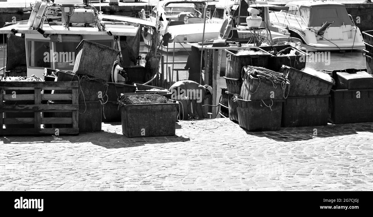 Pesaro, Italien - 09. juli 2020: Ein Fischer arbeitet auf seinem Fischerboot im Hafen von Pesaro mit Werkzeugen des Handels, Fischernetzen und Kisten Stockfoto