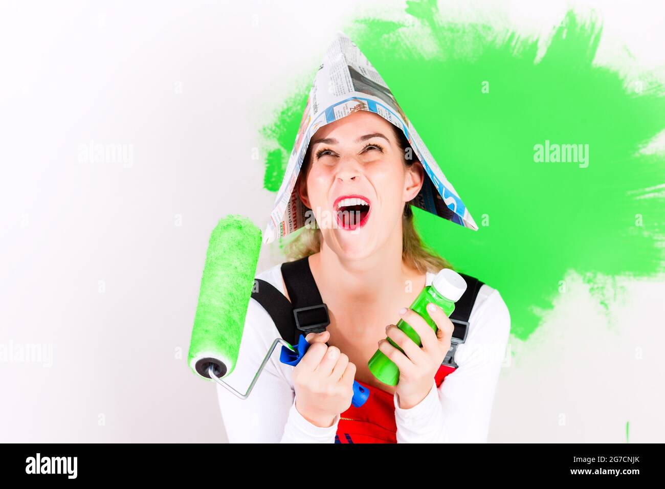 Frau Spaß zu Hause Verbesserung Malerei Wand mit grüner Farbe und Pinsel Stockfoto