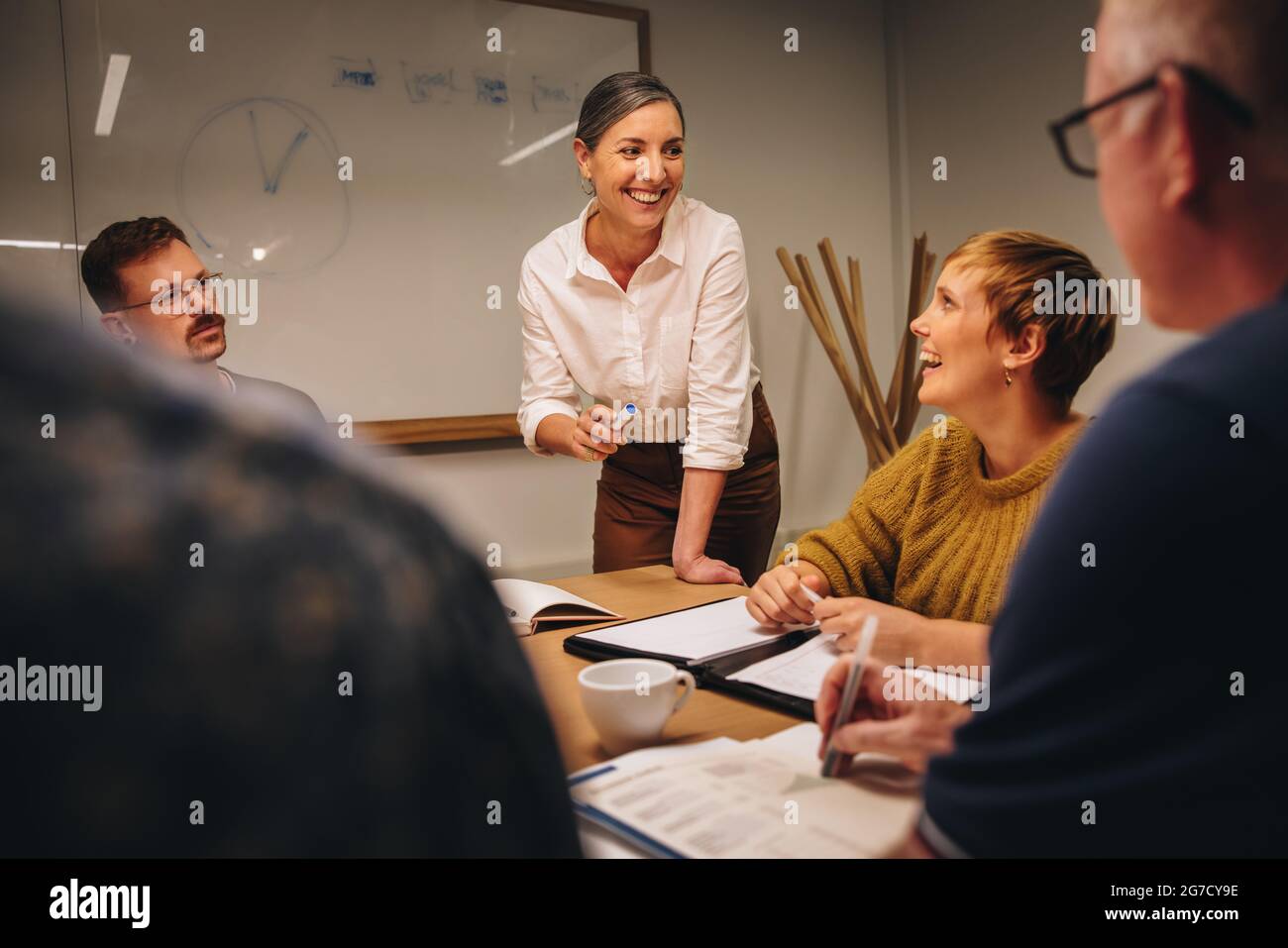 Lächelnde Geschäftsfrau, die ihre Ideen mit dem Team im Meeting teilt. Manager leitet eine Besprechung im Sitzungssaal des Büros. Stockfoto