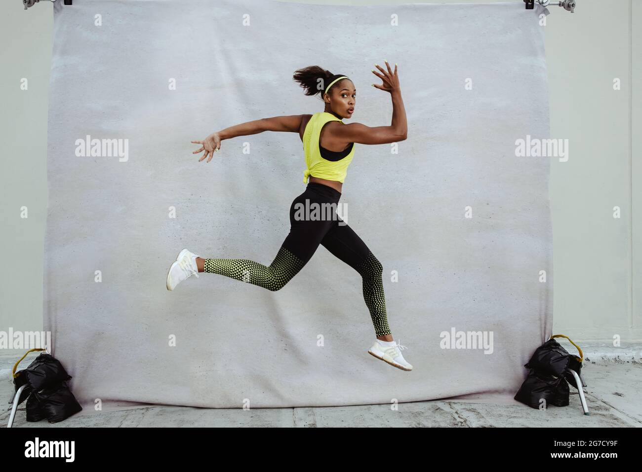 Frau in Sportkleidung Laufen und Springen. Sportlerin beim Training auf einer Gebäudeterrasse. Stockfoto