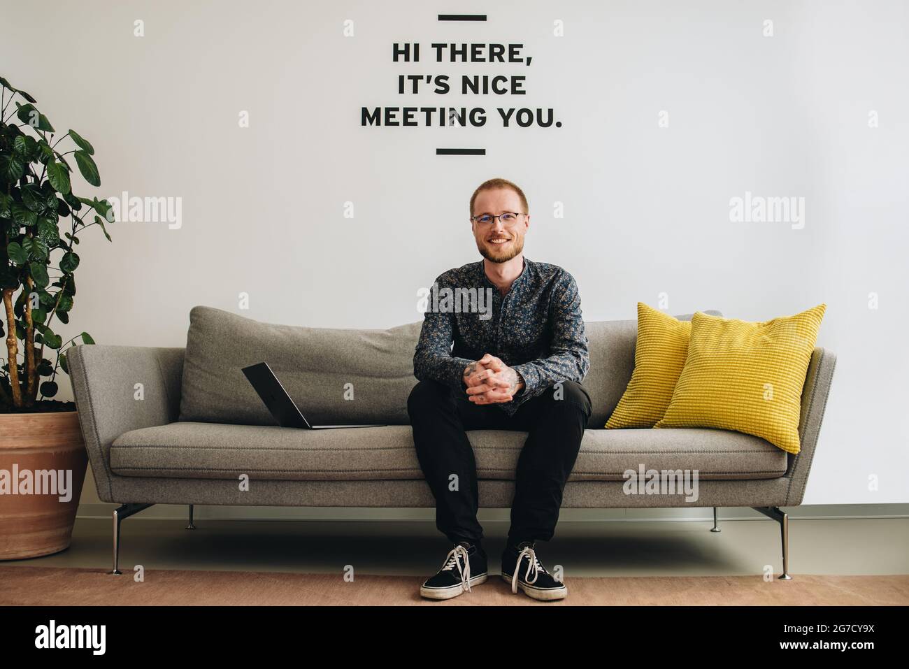 In der Bürolobby sitzt ein positiver Mann auf dem Sofa. Selbstbewusster Unternehmer in der Lobby. Stockfoto