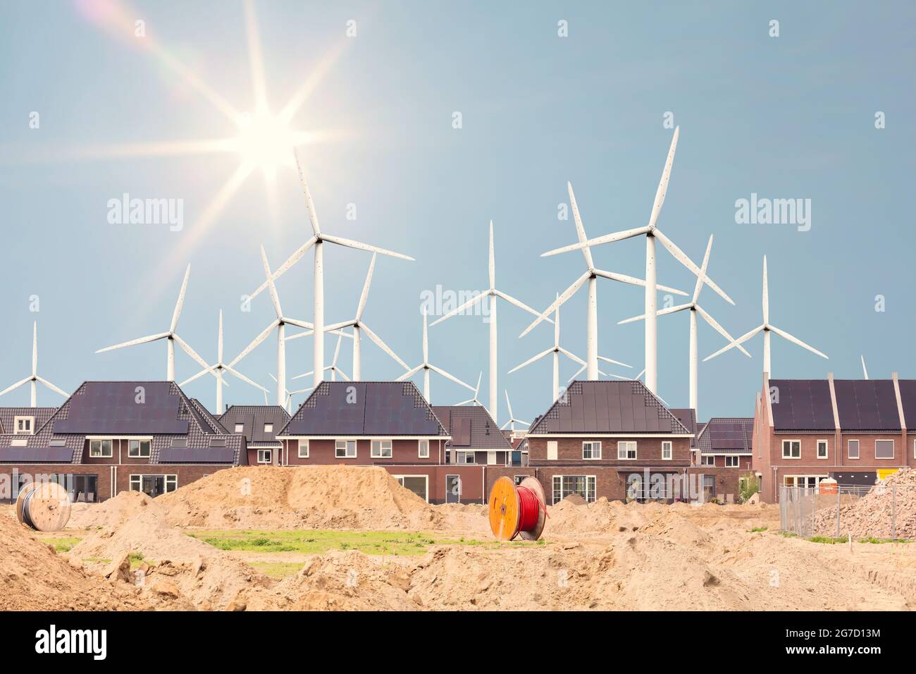 Konzept einer Baustelle für neue niederländische Familienhäuser mit großen Windturbinen und Sonne im Hintergrund Stockfoto