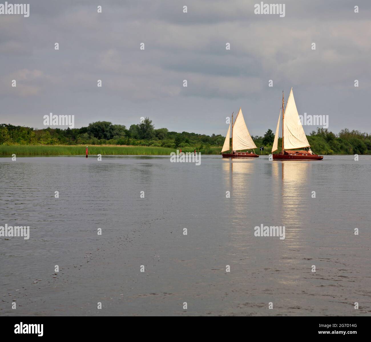 Ein Paar von traditionellen Segelyachten der Hustler-Klasse mit 2 Liegeplätzen auf Barton Broad auf den Norfolk Broads in Barton Turf, Norfolk, England, Großbritannien. Stockfoto