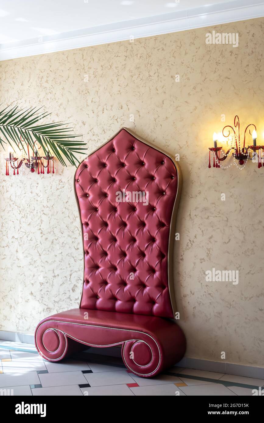 Roter Sessel neben der Wand mit Kronleuchtern im Theatersaal Stockfoto