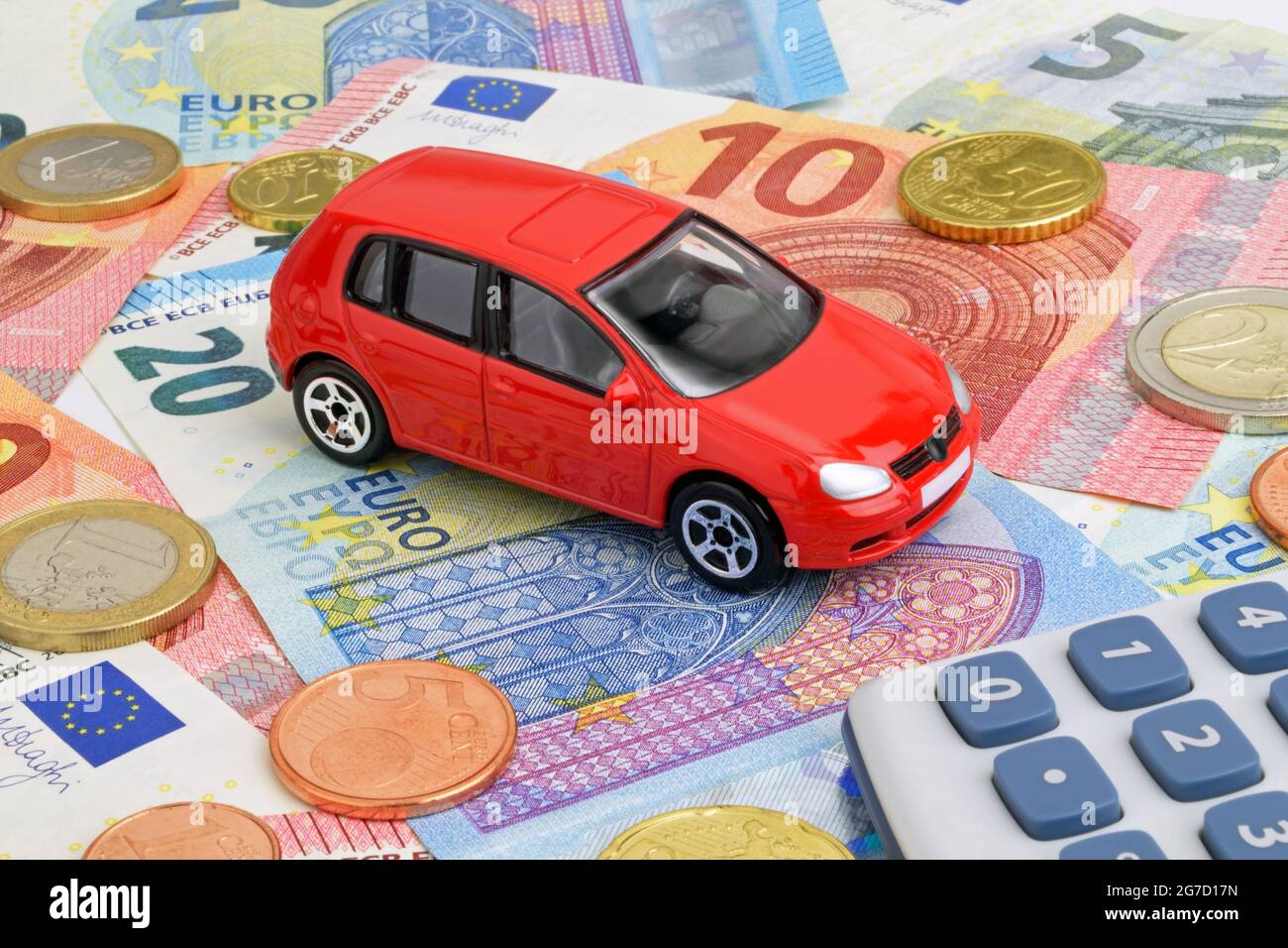 Ein rotes Auto auf Euro-Geldscheinen und -Münzen, das die Fahrzeugfinanzierung darstellt. Stockfoto