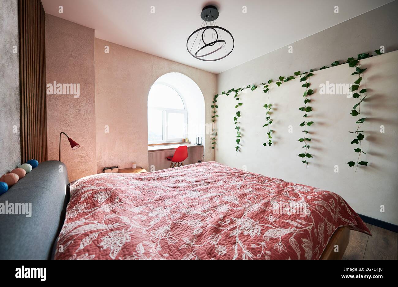 Seitenansicht der modernen Möbel mit großem Bett in bunten Farben, trendigen Lampen und hellem Licht vom Fenster. Konzept der modernen Innenausstattung im Schlafzimmer. Stockfoto