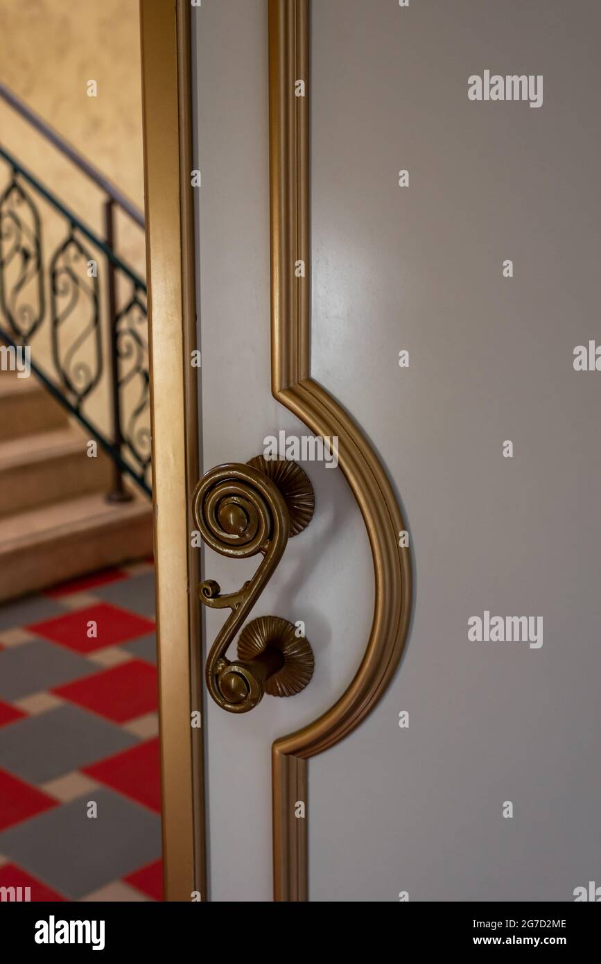 Elegante Tür mit goldenem Dekor und Vintage-Knopf in der Halle Stockfoto