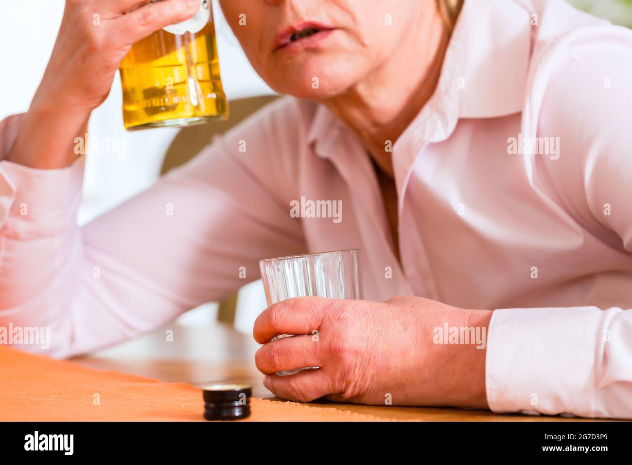 Alte Frau mit Alkohol Problem zu Hause trinken Schnaps sitzen Stockfoto