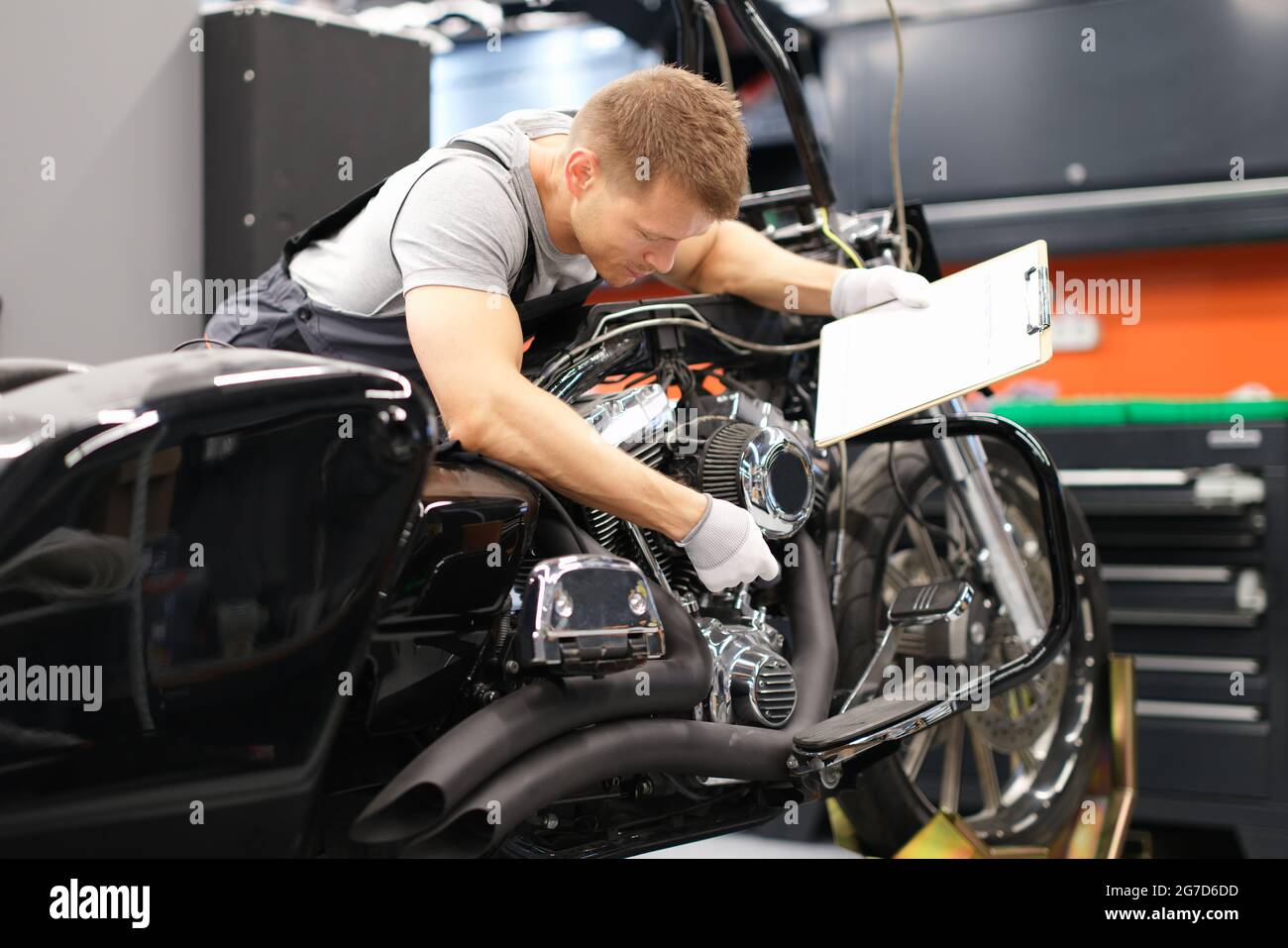 Männlicher Mechaniker diagnostiziert Teile am Motorrad im Service-Center Stockfoto