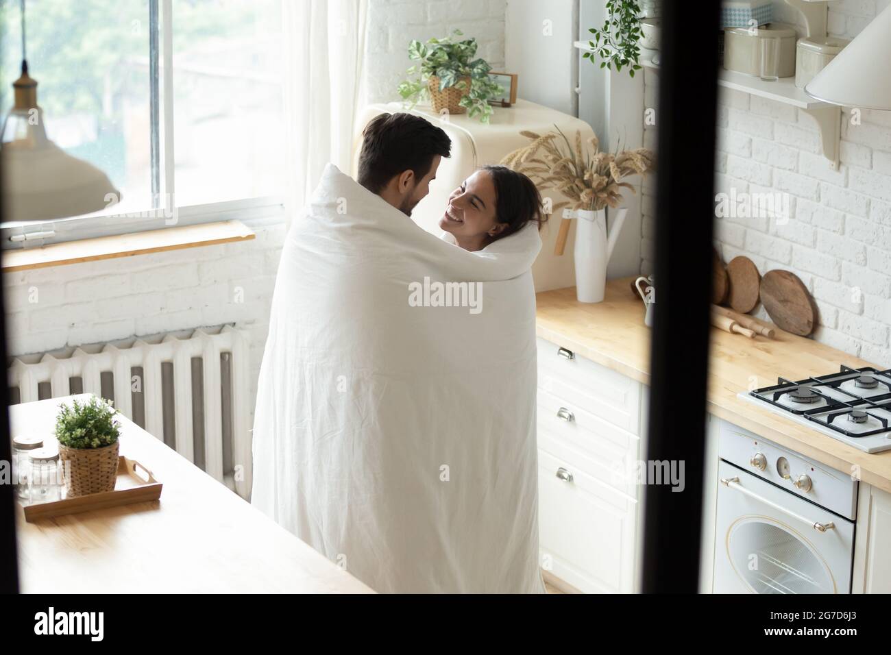 Liebevolles Paar, das in einer modernen Küche in einer Decke zusammengehüllt steht Stockfoto