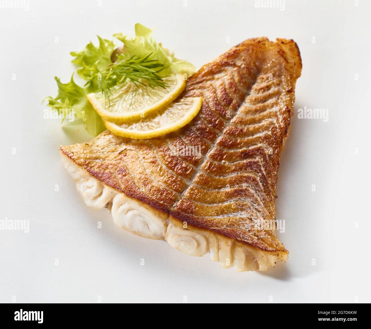 Von oben appetitlich gerösteter Pollack-Fisch auf weißer Oberfläche mit reifen Zitronenscheiben angeordnet Stockfoto