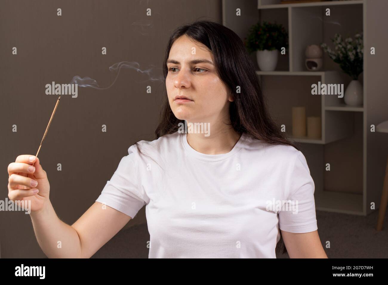 Eine schöne Frau hält einen aromatischen Stock in der Hand. Aromatherapie, aromatischer indischer Rauch und Weihrauch Stockfoto