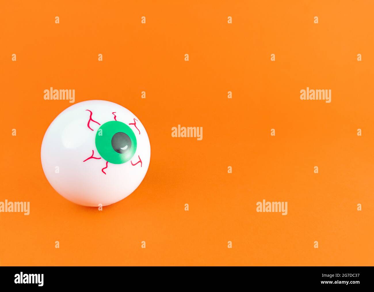 Ein beängstigender Augapfel auf einem orangefarbenen Hintergrund mit Kopierfläche. Stockfoto