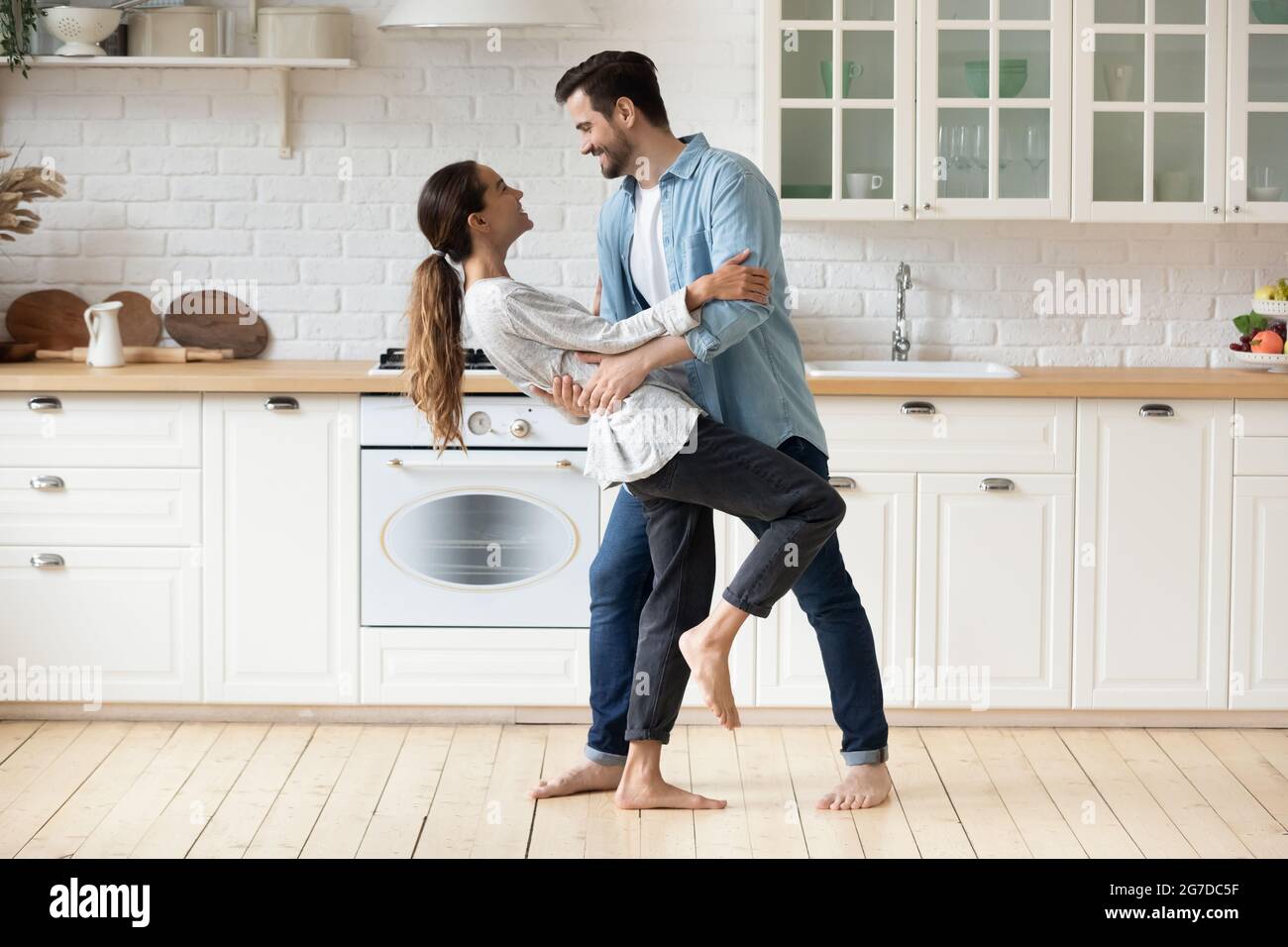 Das junge Paar feiert in der modernen gemütlichen Küche barfuß hauswarmtanzend Stockfoto