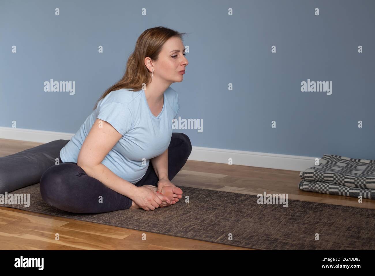 Eine Schwangere, die morgens Yoga macht, sitzt in Baddha Konasana oder Bound Angle Stockfoto