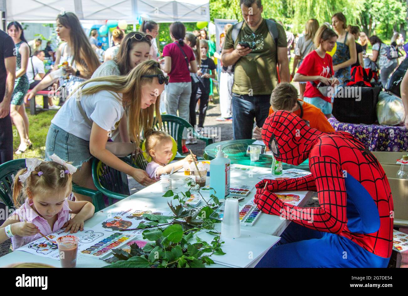 Zaporizhia, Ukraine- 19. Juni 2021: Charity Familienfest: Kinder, Eltern und Freiwillige, gekleidet wie Superhelden, die bunte Zeichnungen machen Stockfoto