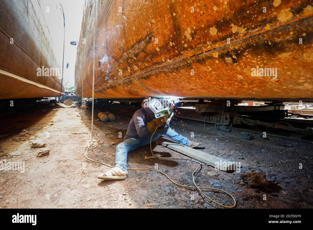 Arbeiter aus Bangladesch reparieren ein Schiff auf einer Werft am Ufer des Flusses Buriganga in Keraniganj, in der Nähe von Dhaka, Bangladesch, Juli 13, 2021. Mit einem Increa Stockfoto