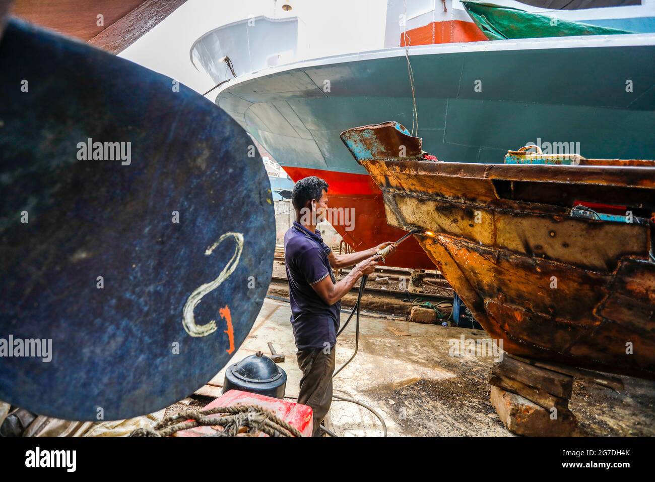 Arbeiter aus Bangladesch reparieren ein Schiff auf einer Werft am Ufer des Flusses Buriganga in Keraniganj, in der Nähe von Dhaka, Bangladesch, Juli 13, 2021. Mit einem Increa Stockfoto