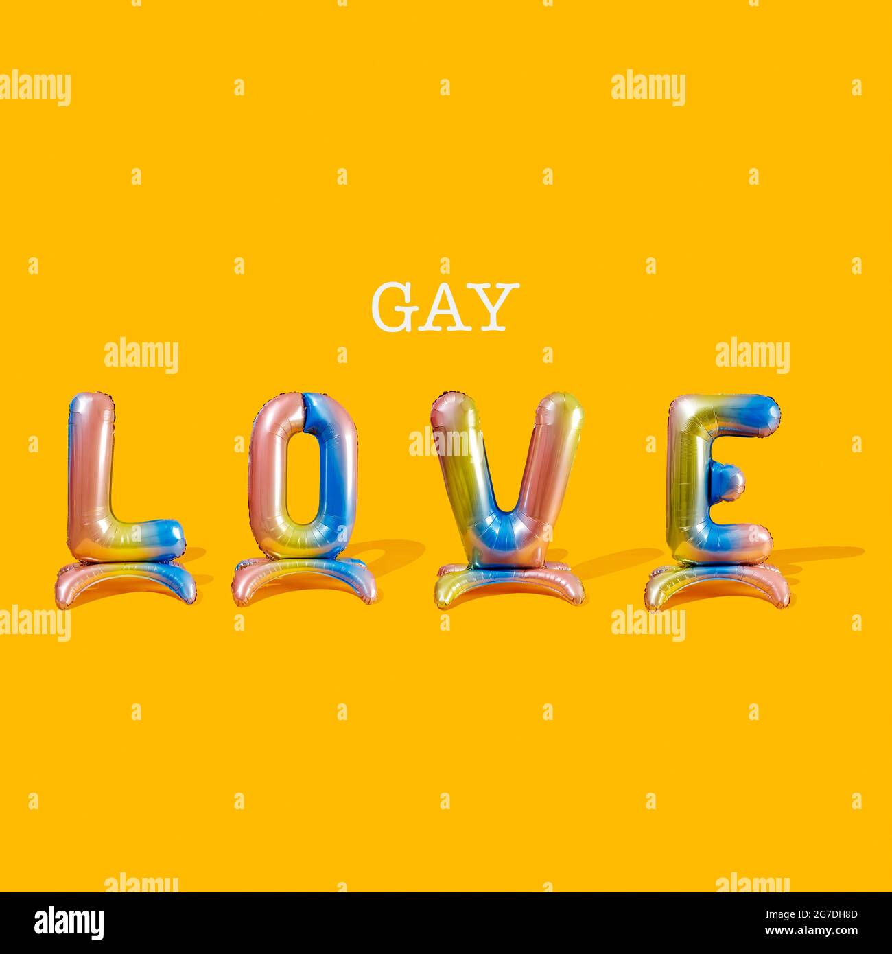 Vier bunte, buchstabenförmige Luftballons und das Wort Gay bilden den Text Gay Love auf einem orangisch-gelben Hintergrund Stockfoto