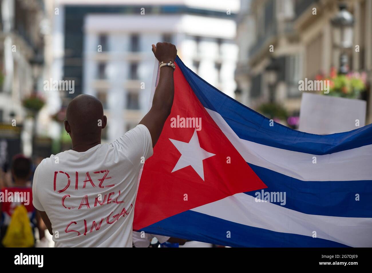 Ein Mann sah, wie er ein T-Shirt gegen Diaz Candel trug und eine kubanische Flagge hochhielt, als er an einem Protest zur Unterstützung der kubanischen Bevölkerung entlang der Straße Marques de Larios teilnahm. Eine Gruppe kubanischer Einwohner in Malaga marschierte entlang der Hauptstraßen in der Innenstadt, um gegen die Regierung des kubanischen Präsidenten Miguel Diaz Canel zu demonstrieren, nachdem der soziale Zusammenbruch in Kuba das Ende der kommunistischen Diktatur gefordert hatte. Stockfoto