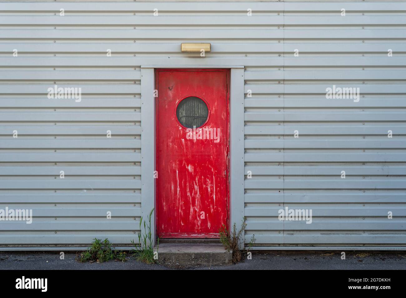 Rote Tür mit Glasfenster. Industriegebäude. Stockfoto