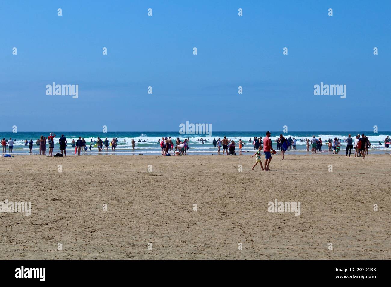 Der Sonnenschein bringt die Massen am Perranporth Strand hervor, während die soziale Distanz an der Tafel vorbei geht. Stockfoto