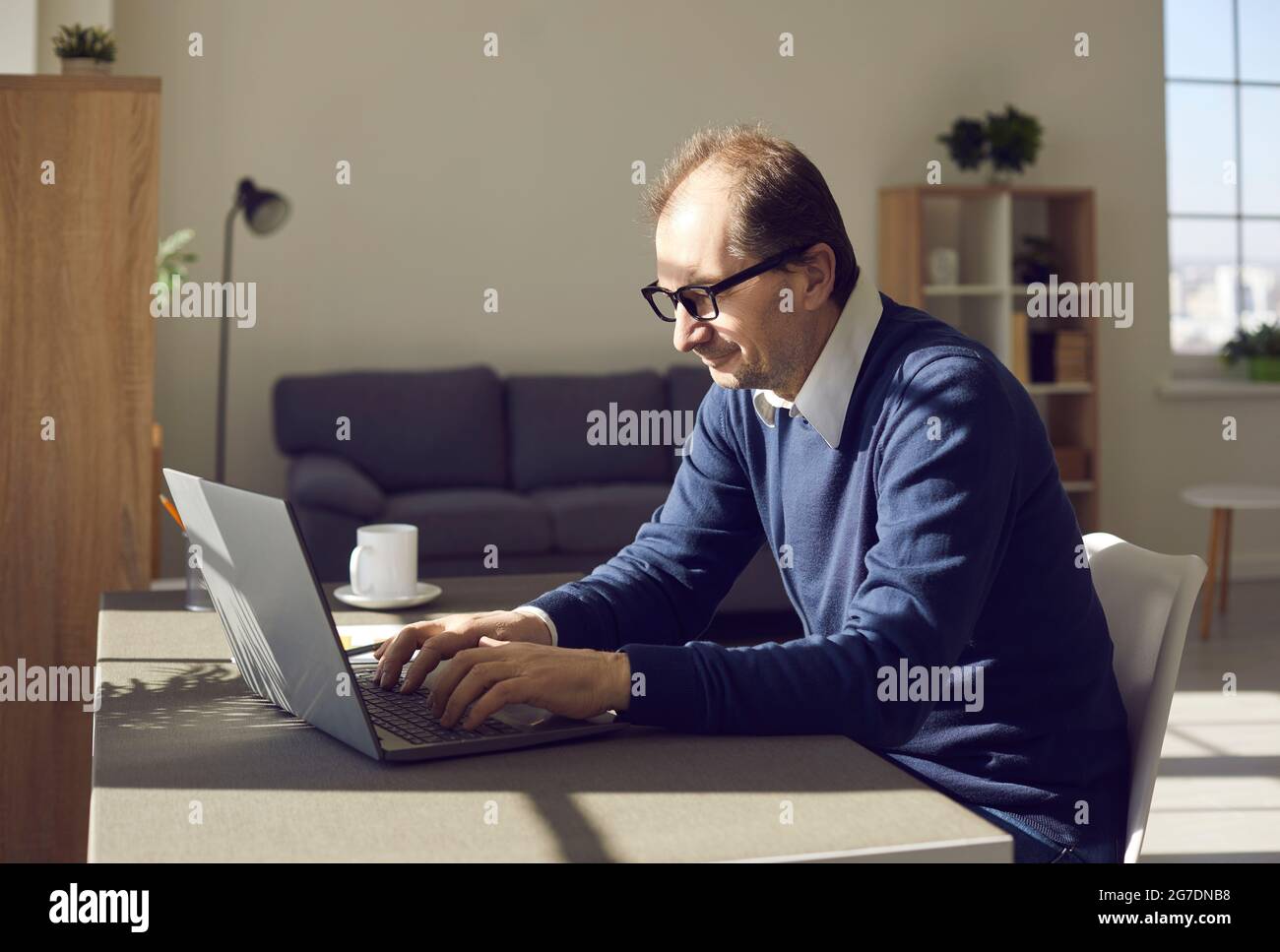 Seitenansicht eines reifen Mannes in einer Brille, der im Heimbüro an einem Laptop arbeitet Stockfoto