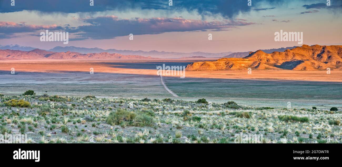 Unbefestigte Straße, die das Dugway Valley durchquert, virga-Luftschlangen verdunstenden Regens unter Wolken, Sonnenaufgang, vom Pony Express Trail, Great Basin, Utah, USA Stockfoto