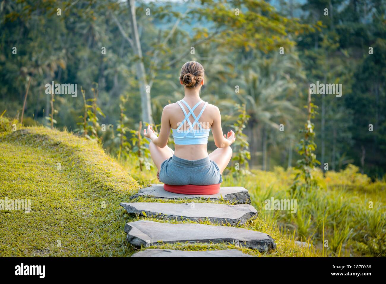 Junge Frau auf dem Weg in den tropischen Dschungel im Lotussitz Yoga tun Entspannungsübungen Stockfoto