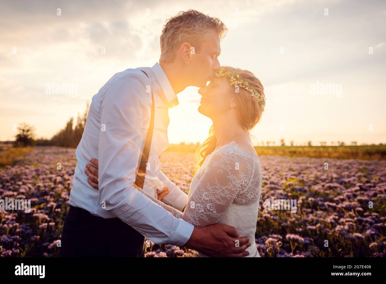 Bräutigam küsst seine Braut während einer romantischen Hochzeit im Dorf in einer romantischen Umgebung Stockfoto