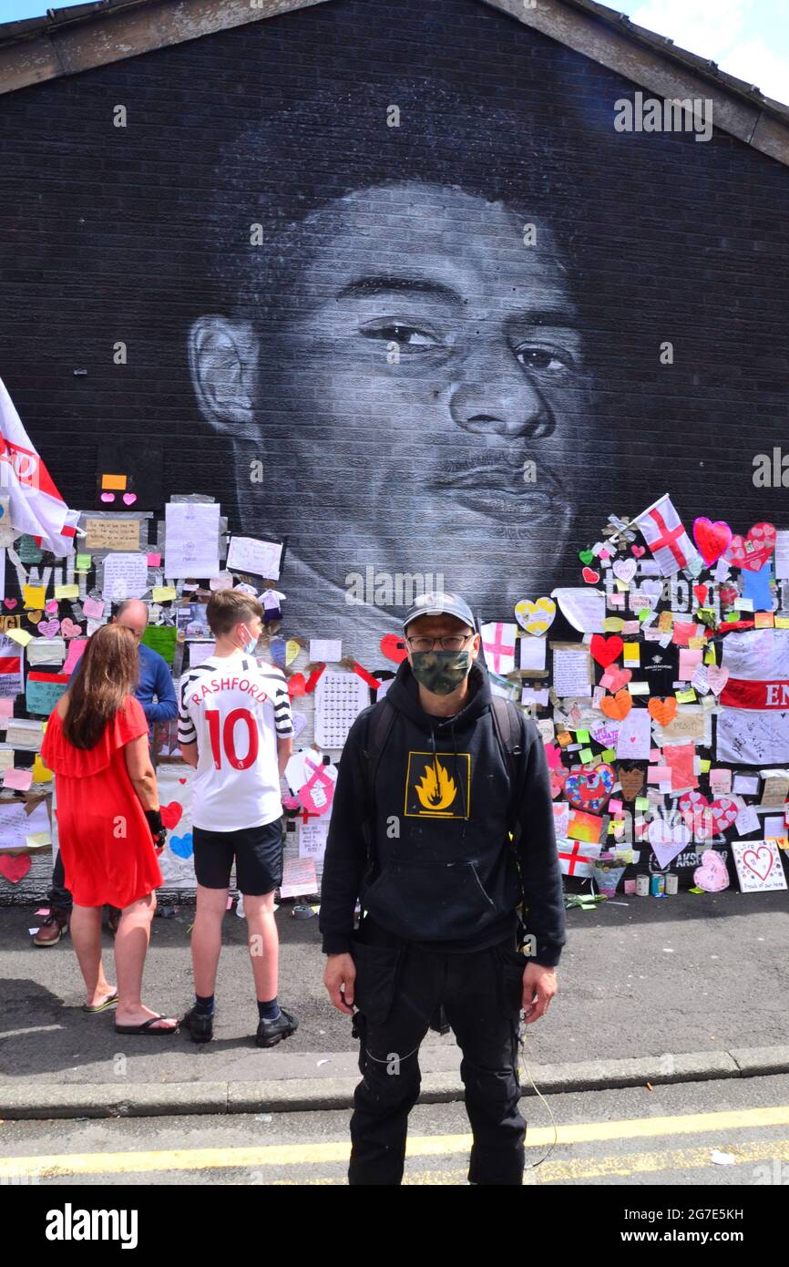 Straßenkünstler Akse P19 vor dem riesigen Manchester United-Spieler Marcus Rashford Wandgemälde in Withington, Manchester, England, Großbritannien, das er malte. Das Wandbild wurde nach dem Verlust der englischen Fußballeuropéen20 am 11. Juli 2021 mit missbräuchlichen Graffiti verwüstet. Das Wandbild wurde von dem in Frankreich geborenen Straßenkünstler Akse an der Wand des Coffee House Cafe in der Copson Street geschaffen. Marcus Rashford ist ein Fußballspieler von Manchester United. Akse reparierte das beschädigte Wandbild bis zum 13. Juli 2021 vollständig. Bilddatum: 13. Juli 2021. Stockfoto